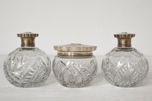 Tres botellas de vidrio tallado con tapa plateada